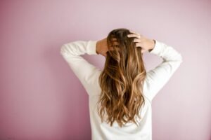 Femme de dos, les mains dans ses cheveux longs